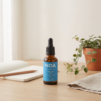 בקבוק NOA BrainBoost™ 30 מ"ל על שולחן לימודים עם מחברת