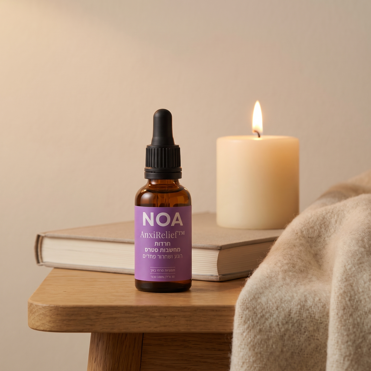 בקבוק NOA AnxiRelief™ 30 מ"ל על שולחן צד עם ספר ונר