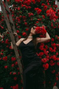 Woman Posing against a Red Rosebush