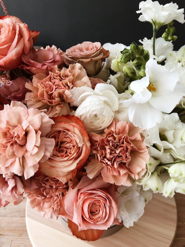 High angle of delicate bunch of fresh pink and white floribunda flowers on wooden floor