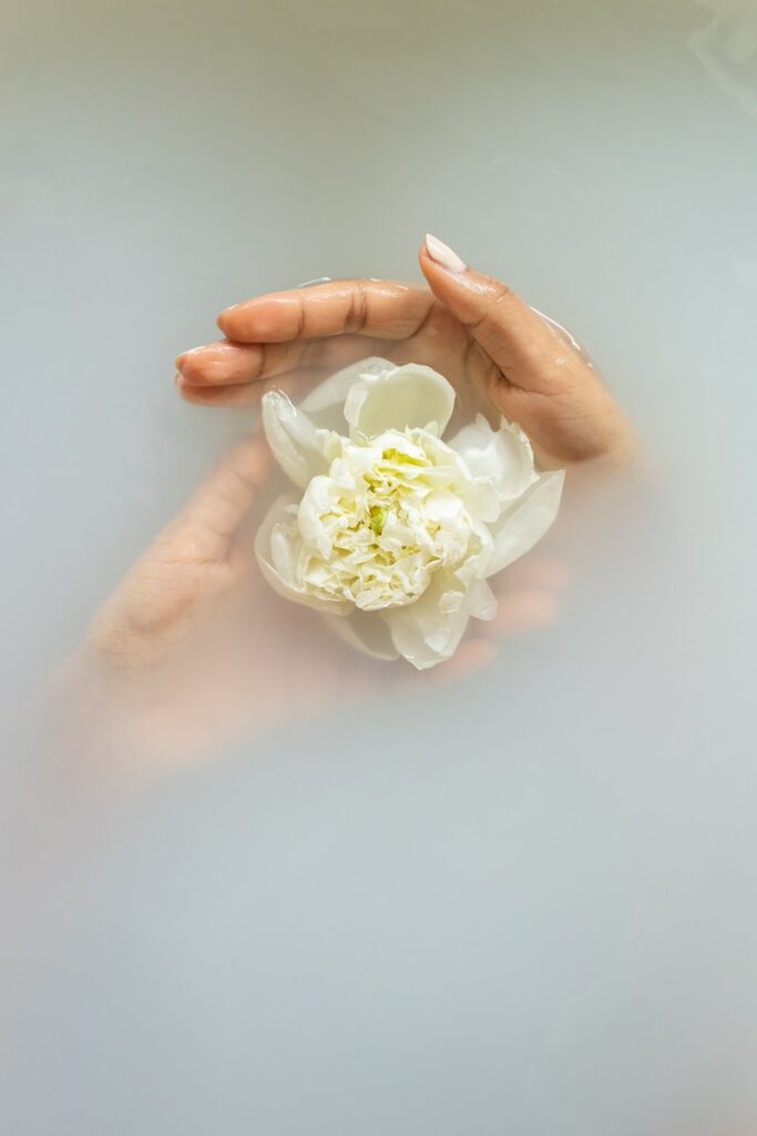Anonymous woman with gentle white flower in water