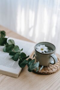 Cup of tea on table near book and plant stem